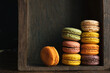 Stack of classic delicious macaroons or macarons in a dark drawer of an old sideboard, close-up