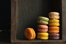 Stack Of Classic Delicious Macaroons Or Macarons In A Dark Drawer Of An Old Sideboard, Close-up