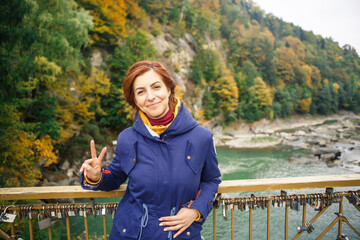 young beautiful girl traveler make a photo on the background of the river and forest