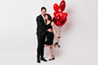 © Look! - Full length portrait of couple posing in valentine's day on white background. Indoor shot of girl with balloons embracing with boyfriend.