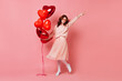 © Look! - Full length shot of blissful woman with red balloons. Studio photo of beautiful ginger girl dancing on pink background.