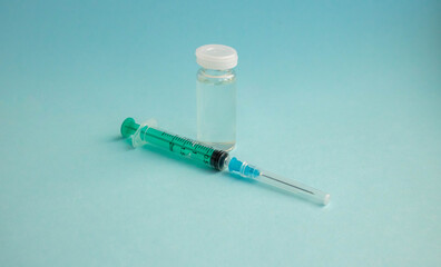 A syringe and a bottle of vaccine stand on a blue background. For the prevention, immunization and treatment of coronavirus infection. The concept of medicine and health care