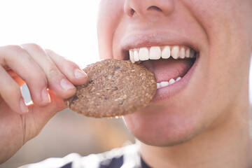 Happy young man eating cookie while smiles