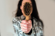 Mujer joven sujetando con la mano un cepillo lleno de pelo caído. Concepto de caída del cabello