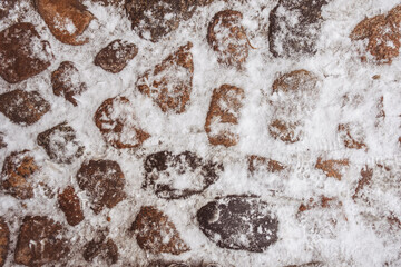 Old stone pavement covered with snow in winter