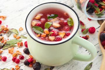 Wall Mural - Green cup of healthy fruit tea with apples, orange, red and black currant berries.