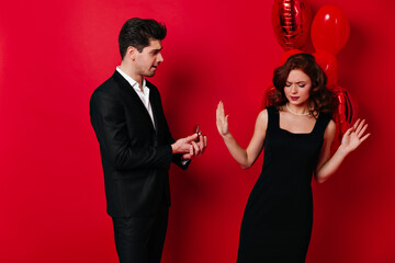 Wall Mural - Ginger girl rejects proposal. Studio photo of upset couple posing in valentine's day.