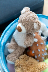 Wall Mural - High angle shot of a teddy bear with other stuff toys on a blue basket