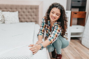 Beautiful and happy middle age woman choosing new bed and mattress in big furniture store