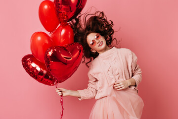 Wall Mural - Relaxed caucasian lady dancing with heart shaped balloons. Indoor photo of female model celebrating valentine's day.