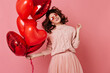 © Look! - Stunning girl having fun in valentine's day. Studio photo of carefree lady isolated on pink with red balloons.