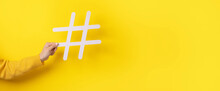 Social media concept, hand holding big white hashtag symbol,  panoramic image