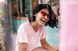 © Look! - Laughing dark-haired woman posing in sunglasses. Outdoor shot of excited tanned girl expressing positive emotions.