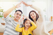 © Tom Wang - Happy asian family forming house roof with their hands at home