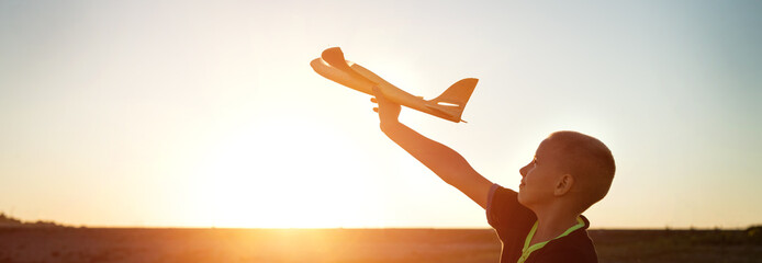 Wall Mural - boy launches the plane on a background of sunset sky