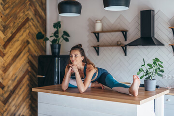 Wall Mural - Flexible athletic woman sitting on a table at home