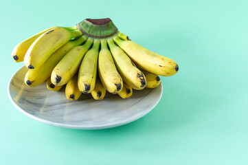 Wall Mural - Ripe tasty banans on a plate on blue background. Healty eating concept