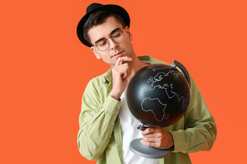 Male tourist with globe on color background