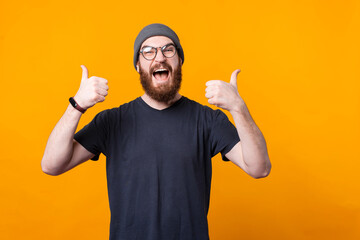 Wall Mural - An very excited man with beard and glasses is showing thumbs up at the camera .