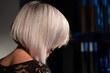 A woman's platinum blonde straight hair hairstyle on modern dark background with blue led lights