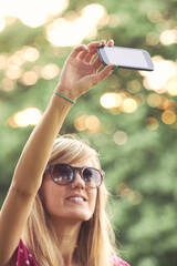 Wall Mural - Young woman using modern smartphone outdoors.