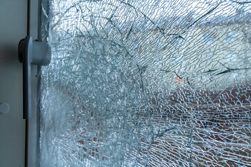 Broken balcony glass door window with shattered glass