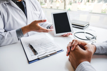 Wall Mural - Doctor consulting with patient presenting results on digital tablet tablet sitting at table