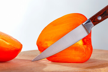 Fresh persimmon fruit and knife on wooden cutting board. Vitamin natural food.