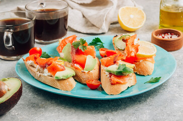 Wall Mural - Smoked salmon sandwich with cream cheese, lemon, avoado and tomato on gray background. Selective focus