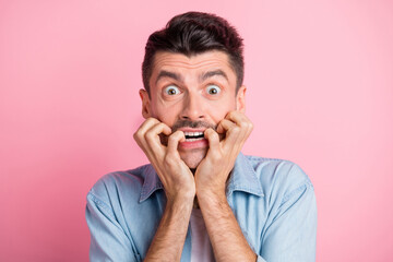 Poster - Photo of scared shocked young man bite nails hold hands mouth isolated on pastel pink color background