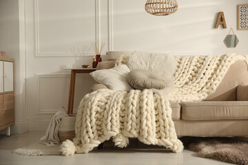 Wall Mural - Cozy living room interior with beige sofa, knitted blanket and cushions