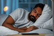 people, bedtime and rest concept - indian man sleeping in bed at home at night