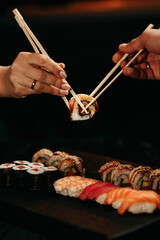 Close-up, couple hands eating sushi food with chopsticks