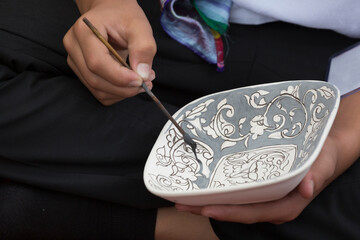 Artist paints a ceramic plate. Uzbekistan