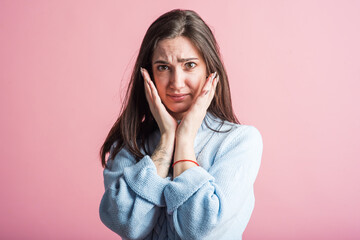 Wall Mural - Scared brunette girl in studio on pink background