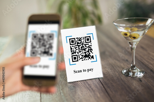 Women\'s hands are using the phone to scan the qr code to pay drink. Scan to get discounts or pay for drink. The concept of using a phone to transfer money or paying money online without cash.
