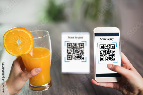 Women\'s hands are using the phone to scan the qr code to pay juice. Scan to get discounts or pay for juice. The concept of using a phone to transfer money or paying money online without cash.