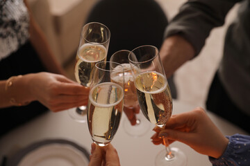 People clinking glasses with champagne at home, closeup