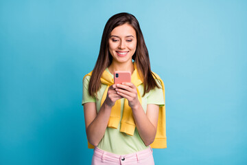 Sticker - Photo of young beautiful happy positive cheerful smiling girl using smartphone isolated on blue color background