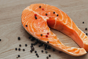 Fresh salmon steak on a wooden board with spices and pepper. Preparing for cooking.