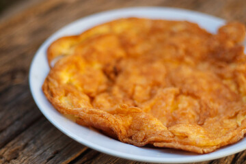 Crispy golden yellow omelette with plates on an old wooden floor is another simple dish in Thailand.