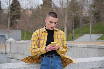 Handsome young man wearing make up, chatting on his smartphone. Non binary androgynous guy.