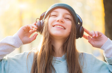 Wall Mural - Smiling teenage girl in headphones outdoors