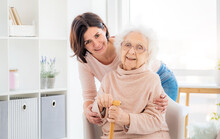 Happy Elderly Woman Embraced By Daughter At Home