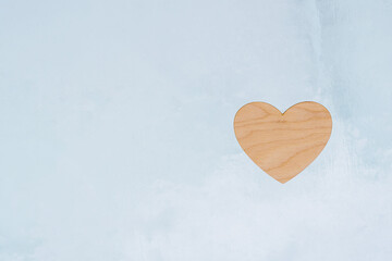 Poster - Valentine's Day, a wooden heart lies on an icy abstract background.