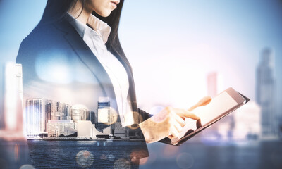 Wall Mural - Pretty businesswoman using tablet on abstract city background.