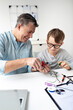 © epiximages - Father and son repairing an electrical outlet.