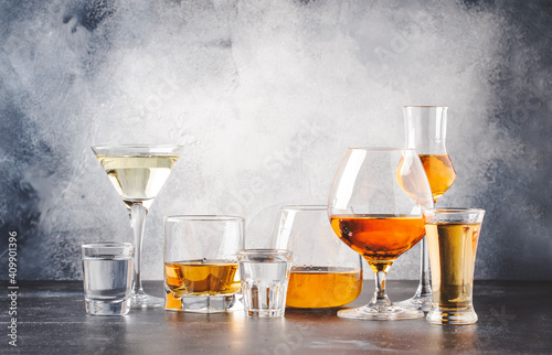 Strong alcoholic drinks in glasses in assortment: vodka, cognac, tequila, brandy and whiskey, grappa, liqueur, vermouth, tincture, rum. Gray bar counter with copy space © 5ph