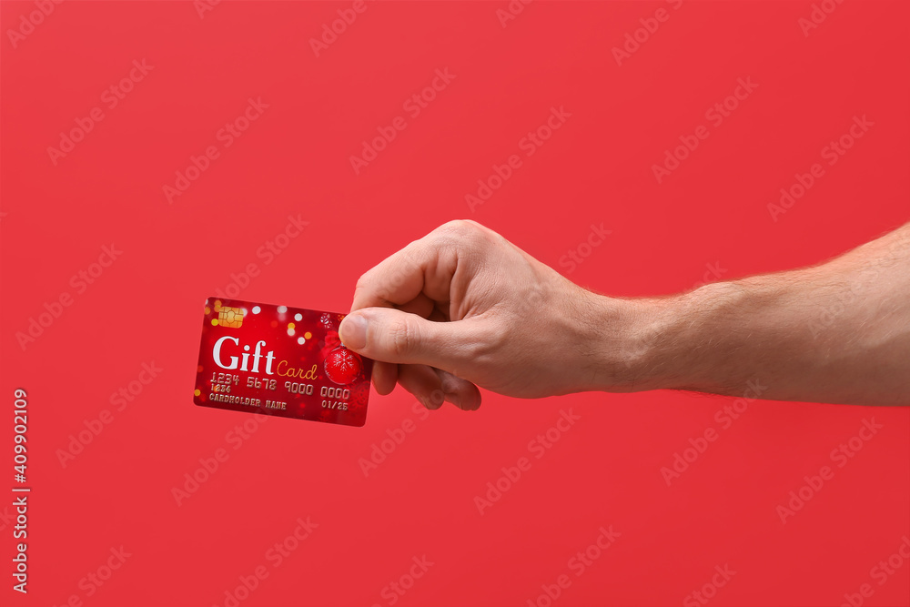 Hand with gift card on color background