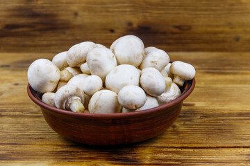 Poster - Fresh champignon mushrooms in ceramic bowl on the wooden table